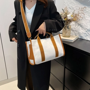 Minimalist white canvas tote bag with tan trim and shoulder strap on model