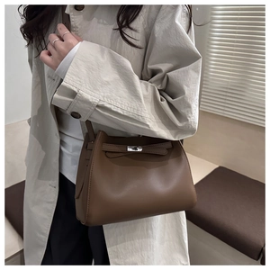 Detalle del bolso tipo cubo en cuero marrón con cierre de metal y diseño trapezoidal
