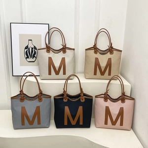 Minimalist woven tote bags with leather M patch in five colors on a white display