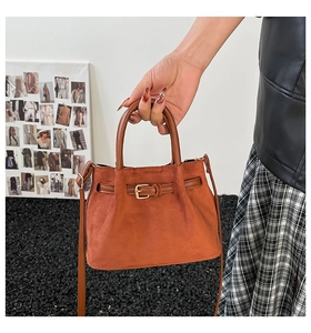 Close-up of caramel suede bucket bag with metal buckle and adjustable shoulder strap