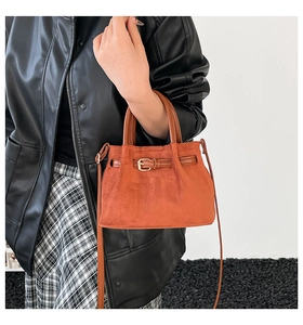 Detail of the orange-brown suede bucket bag with leather strap and top handle