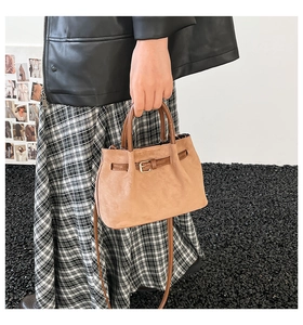 Close-up of brown suede bucket bag featuring elegant gold metal buckle and leather strap