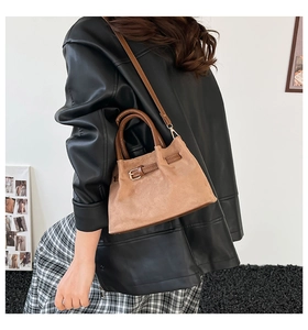 Brown vintage bucket bag in frosted leather texture worn by a model in a stylish leather outfit