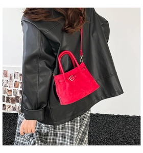 Model wearing a red suede mini bucket bag with strap in a stylish red and black outfit