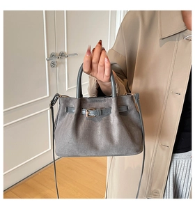 Detail of grey suede bucket bag showing gold buckle and detachable shoulder strap