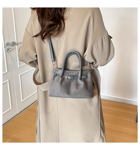 Detail of grey suede bucket bag with buckle strap and detachable shoulder strap