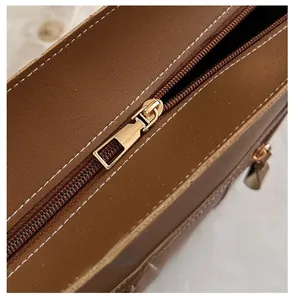 Detailed close-up of the smooth gold metal zipper on a brown vintage leather handbag
