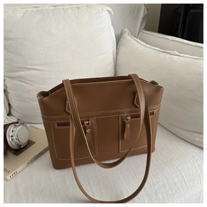 Detail of a brown tote bag featuring dual front zipper pockets and white contrast stitching