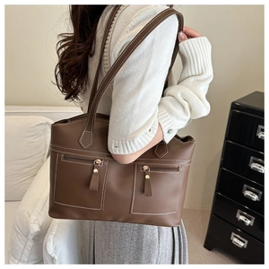 Detail of a brown retro tote bag featuring dual front zipper pockets and white contrast stitching