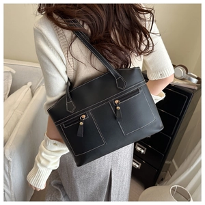 Detail of black tote bag with white contrast stitching and two front zipper pockets