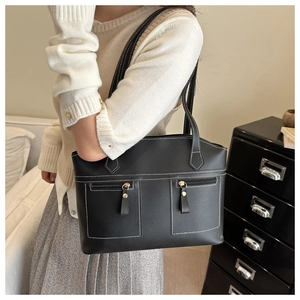 Close-up of black tote bag with white contrast stitching and zippered pockets