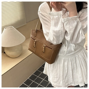 Detail of brown tote bag featuring white contrast stitching and twin zipper pockets