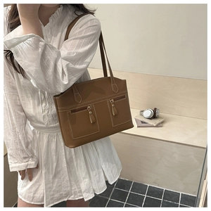 Detail of brown matte leather tote bag featuring white contrast stitching and front pockets