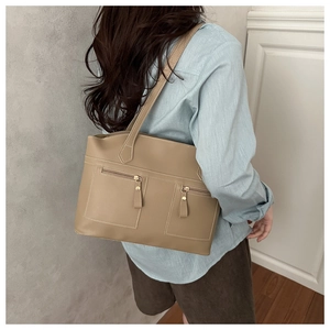 Detail of khaki tote bag with dual front zippers and textured faux leather finish