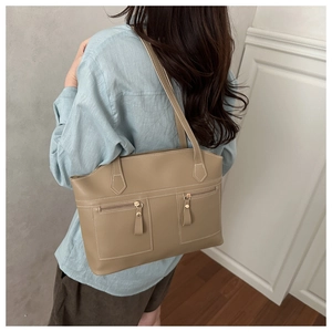 Detail of khaki leather shoulder bag featuring white contrast stitching and dual front zippers