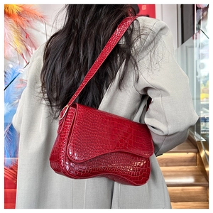 Macro shot of bright red faux leather bag featuring elegant crocodile skin embossing