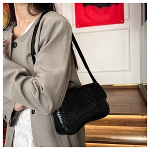 Detail of black crocodile pattern shoulder bag with glossy faux leather texture