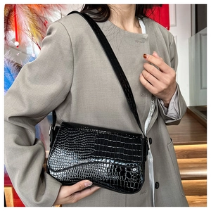 Side view of black crocodile pattern shoulder bag worn by model for daily styling