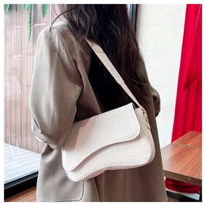 Detail view of cream crocodile pattern saddle bag worn on shoulder by model
