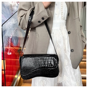 Detail of French style black crocodile embossed leather bag with hourglass curved base