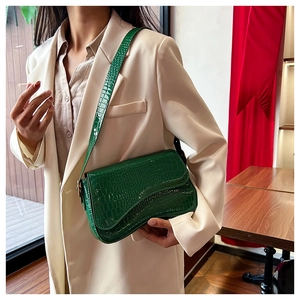 Detail of dark green crocodile pattern leather underarm bag on beige suit jacket
