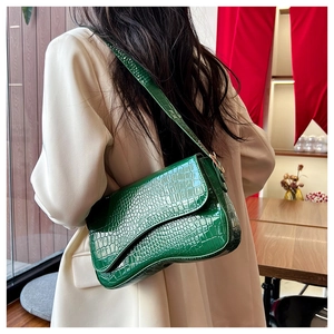 Detailed view of green crocodile pattern saddle bag with unique wavy bottom design