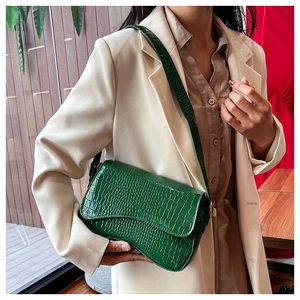 Detail of green crocodile embossed faux leather handbag with sleek gold metal hardware