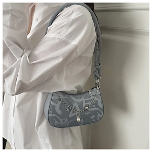 Detail of blue underarm bag featuring abstract letter print and stylish star pearl charm