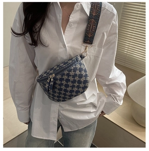 Close-up of navy crescent bag with gold M pattern and bohemian woven shoulder strap