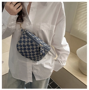 Detail of vintage navy shoulder bag featuring woven letter patterns and sturdy zippers