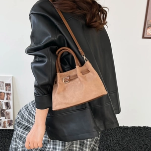 Retro khaki suede bucket bag with contrast brown straps shown from a side view