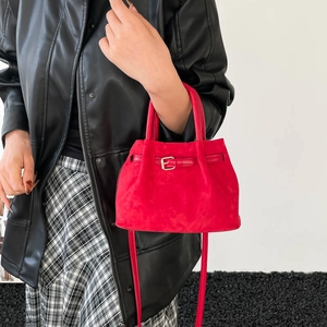 Retro red faux suede bucket bag with top handles and shoulder strap shown on a model