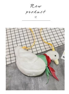 Detailed close-up of white plush duck bag with decorative bows and yellow strap