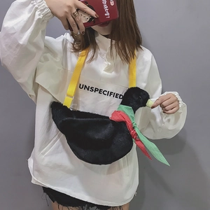 Detail shot of a black plush duck crossbody bag with red plaid scarf on a model