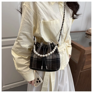 Detail of plaid bucket bag featuring pearl handle and woven metal chain strap