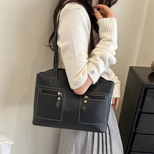 Minimalist black leather tote bag with contrast stitching and dual front zippers