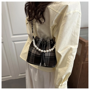 Detailed view of checkered tweed bucket bag with decorative faux pearl handle and drawstring