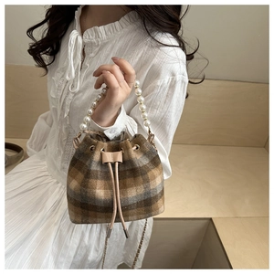 Close-up of vintage check bucket bag featuring pearl handle and leather tassels