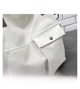 Close-up of white canvas bag showing twill texture, flap pocket and metal snap button