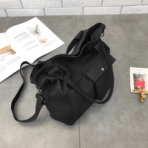 Detail view of black canvas tote bag with front snap pocket and adjustable shoulder strap