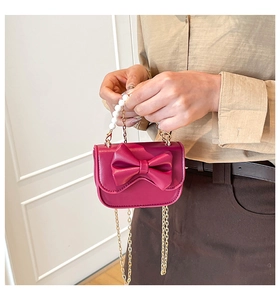 Detail of magenta mini bag with a large bow, pearl handle, and golden metal chain