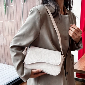 Chic cream crocodile pattern crossbody bag with flap cover shown on a model
