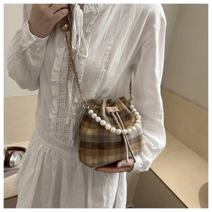 Detail of brown plaid bucket bag with pearl handle and metal leather strap for women