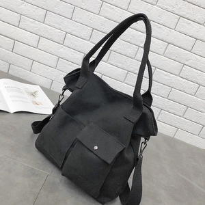 Detail of black canvas tote bag showing utility pockets and adjustable shoulder strap