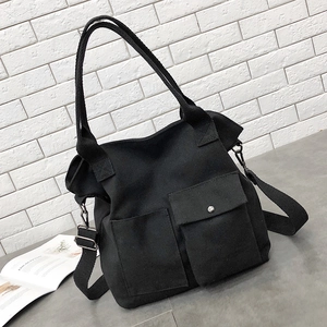 Minimalist black canvas crossbody bag with dual front pockets shown from a 45-degree angle
