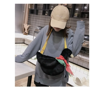 Detail of cute black plush duck crossbody bag worn by model with yellow shoulder strap