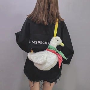 Detail of white plush duck bag featuring a colorful bow tie and adjustable yellow strap