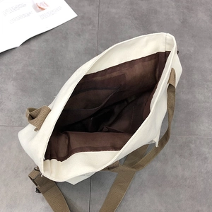 Internal view of a large canvas tote bag featuring a brown zipper pocket and lining