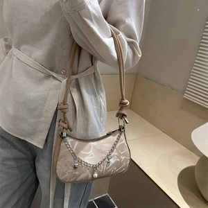 Fashionable beige hobo bag with artistic texture and decorative silver chain and charms