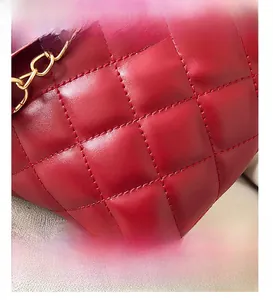 Detail of red quilted faux leather bag featuring fine stitching and a gold chain strap